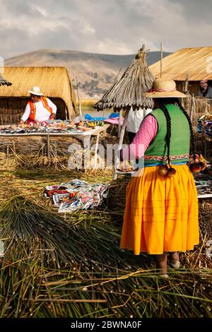 Die Uros-Gemeinschaft zeigt ihr Handwerk, während Touristen ihre schwimmende Insel aus Totorareed am Titicaca-See in Peru besuchen. Stockfoto