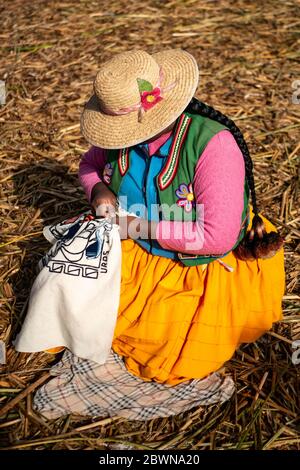 Die Uros-Gemeinschaft zeigt ihr Handwerk, während Touristen ihre schwimmende Insel aus Totorareed am Titicaca-See in Peru besuchen. Stockfoto