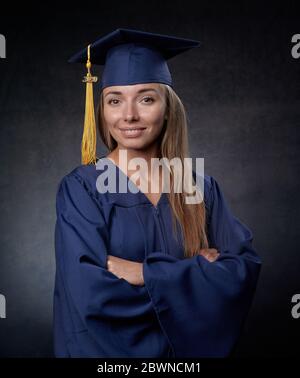 Lächelnde junge Frau Arme gekreuzt tragen blaue Mütze und Kleid Stockfoto