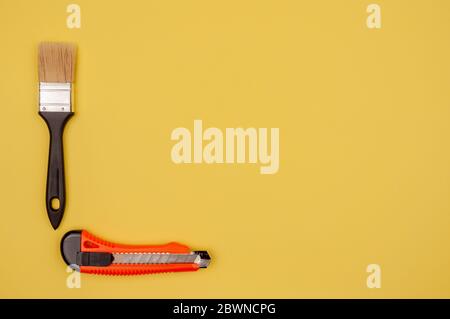 Pinsel zum Malen und Messer auf gelbem Hintergrund. Stockfoto
