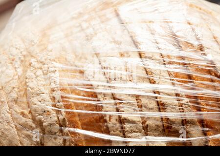 Vorgeschnittenes Brot mit Mehl in einem einfachen durchsichtigen Plastikbeutel Behälter sehen, dicht gewickelt, Makro, Nahaufnahme. Unökologisch nicht umweltfreundlich Stockfoto