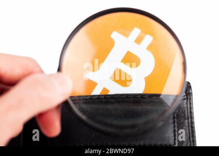 Genauerer Blick auf Bitcoin-Logo, Symbol in einer Brieftasche, Mann, der BTC-Kryptowährung untersucht, Lupe in der Hand. Kryptowährungsbörsen, digitale Speicherung Stockfoto