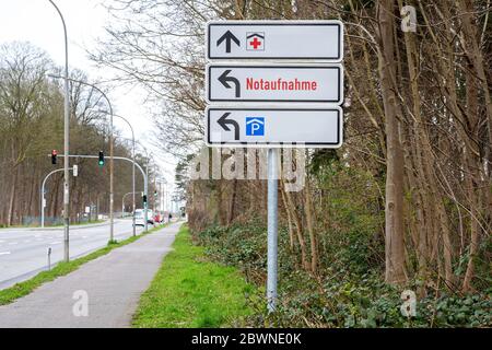 Richtungsschild zeigt rotes Kreuz, Parksymbol und deutschen Text Notaufnahme, was Notaufnahme bedeutet, an der Straße zu einem großen Krankenhaus Stockfoto