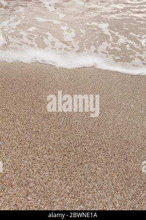 Verschiedene Struktur am Strand - Wasser und Sand, Steine und Kiesel, Wellen und Spritzer. Selektiver Fokus. Stockfoto