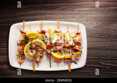 Direkt über Schuss Lachs und Gemüsespieße mit Zitronenspieße, Dill und Schnittlauch in einem Teller serviert Stockfoto