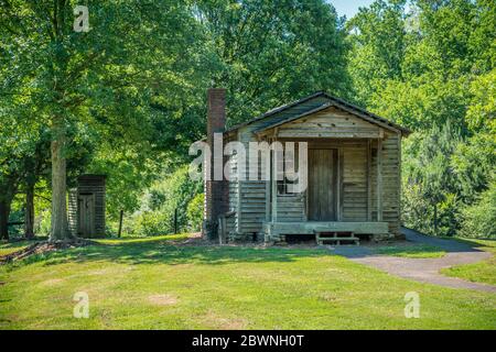 Eine rustikale Holzhütte mit einem Nebengebäude mit Bäumen, die das Gebäude an einem hellen sonnigen Tag im Sommer umgeben Stockfoto