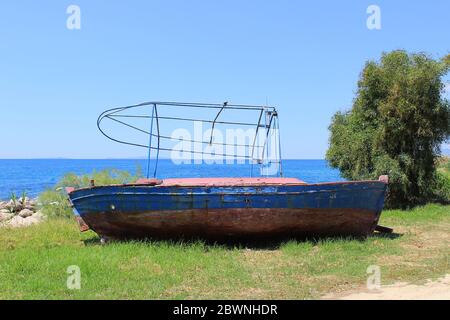 Altes verlassene hölzerne Fischerboot an der Küste. Hintergrund Blick auf das Meer Stockfoto