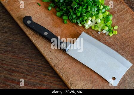 Gehackter Salat auf einem Holzbrett. Ein Küchenheftchen liegt in der Nähe. Der Prozess der Zubereitung von hausgemachten Speisen. Selektiver Fokus. Stockfoto