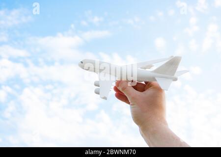 Spielt mit einem Spielzeug Flugzeug in der Hand am Himmel mit Wolken. Reise Inspiration Flug Flugzeug Hand halten Flugzeug. Stockfoto