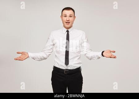 Junger staunend Mann in einem weißen Hemd und schwarze Krawatte mit weit auseinander Arme auf weißem Hintergrund, isoliert. Kopieren Sie Speicherplatz, um das Modell anzukündigen Stockfoto