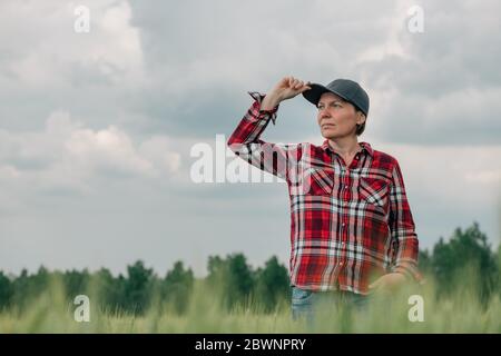 Verantwortungsvolle Weizenbauern Agrarwissenschaftlerin, die ihr kultiviertes Getreideanbau-Agrarfeld ansieht, weibliche Farmarbeiterin posiert auf Ackerland Stockfoto