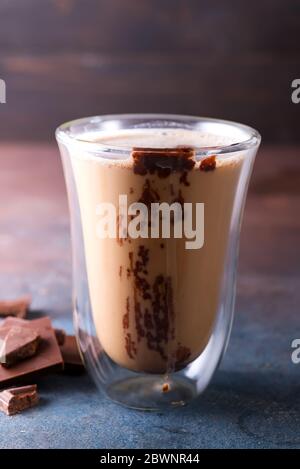 Transparente doppelwandige Glasbecher mit Latte Kaffee mit Schokolade in dunklem Stein Hintergrund Stockfoto