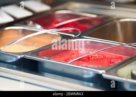 Detail des Innenfensters eines Eisbereiters, das die Tabletts mit verschiedenen Geschmacksrichtungen zeigt. Stockfoto