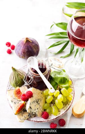 Auswahl an Käse, Beeren und Trauben mit Rotwein in Gläsern auf Steingrund. Kopierbereich Stockfoto