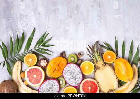 Früchte und Palmblätter auf weißem Hintergrund. Tropische Früchte. Sommerkonzept. Flaches Layout, Draufsicht, Kopierbereich Stockfoto