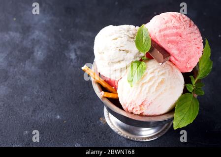 Trio aus leckeren Vanille und Erdbeere aromatisiert gefrorenes Dessert Eis in einer Metallschale mit Minze auf einem Stein Stockfoto