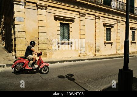 Mann auf einer roten vespa in Noto, Sizilien, Italien Stockfoto