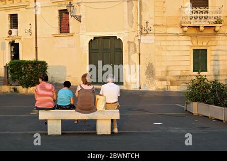 Ältere Menschen sitzen auf der öffentlichen Bank in Syrakus, Sizilien, Italien Stockfoto