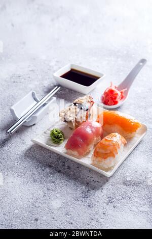 Makro-Schuss von Sashimi, Uramaki und Nachighiri, japanisches Gericht bestehend aus Reis, Lachs oder Thunfisch, Garnelen in Stein. Konzept des japanischen Restaurants Stockfoto