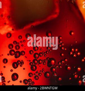 Frische, kochende Cola mit Blasen und Eiswürfeln Hintergrund. Sekt Soda Pop Drink Nahaufnahme. Stockfoto