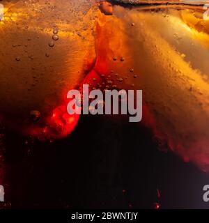 Frische, kochende Cola mit Blasen und Eiswürfeln Hintergrund. Sekt Soda Pop Drink Nahaufnahme. Stockfoto