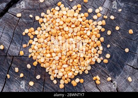 Trockene, gespaltene Erbsen auf einem alten Stumpf verstreut Stockfoto