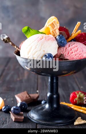 Trio aus leckeren Zitrone, Vanille und Erdbeere aromatisierten gefrorenen Dessert Eis in einer Metallschale mit Waffelstrohhalmen und Beeren auf Holz Stockfoto