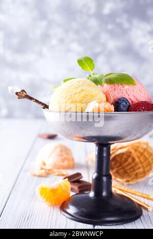 Trio aus leckeren Zitrone, Vanille und Erdbeere aromatisierten gefrorenen Dessert Eis in einer Metallschale mit Waffelstrohhalmen und Beeren auf Holz Stockfoto