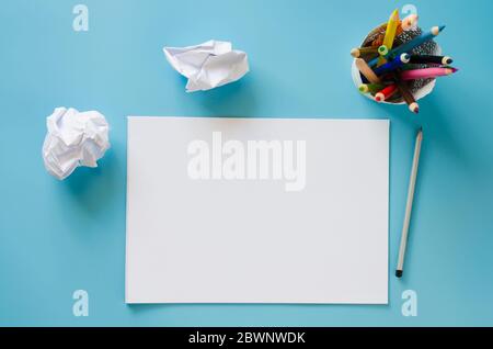 Leeres Notizbuch, Satz von Buntstiften und zerknitterte Papiere auf blauem Hintergrund. Papierhintergrund. Mock-Up. Blick von oben Stockfoto