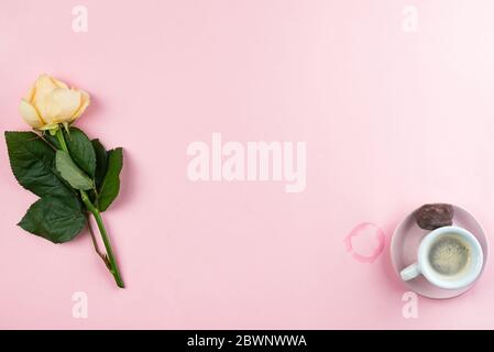 Espresso in einer weißen Tasse mit einer einzelnen Rose auf einem rosa Hintergrund, flach Legeplatz Kopie. Stockfoto