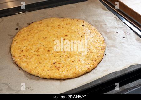 Frisch gebackene Pizzabruste aus geschreddertem Blumenkohl und Käse auf einem Backblech, gesundes Rezept für Schlankheitsmittel mit kohlenarcher oder ketogener Diät, ausgewählt Stockfoto