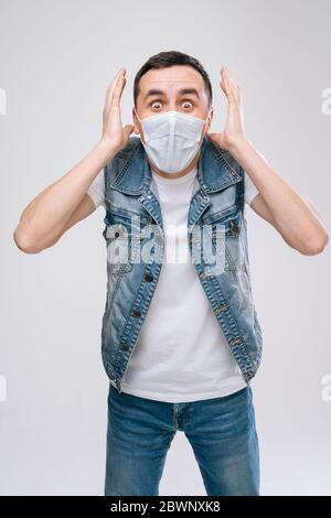 Erschrockter Mann in medizinischer Maske Angst vor etwas und blickt in die Kamera. Stockfoto