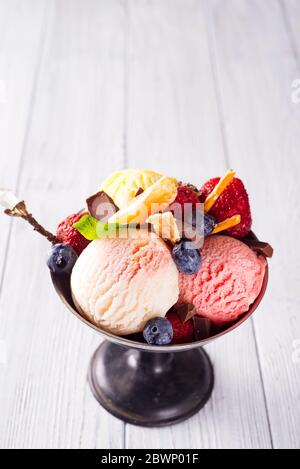 Set von Eis Kugeln in verschiedenen Farben und Geschmacksrichtungen mit Beeren, Schokolade auf Holzhintergrund Stockfoto