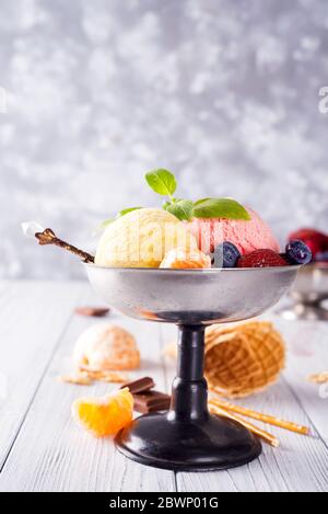 Set von Eis Kugeln in verschiedenen Farben und Geschmacksrichtungen mit Beeren, Schokolade auf Holzhintergrund Stockfoto
