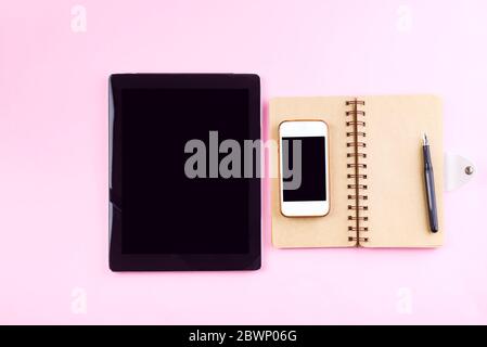 Notizbücher, Tablet, Stift und Smartphone auf einem pastellrosa Hintergrund. Mockup-Konzept für Unternehmen Stockfoto