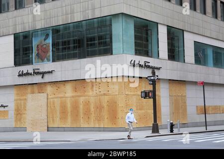 Mann mit Gesichtsschutz und Masken geht durch Luxus-Shop Salvatore Ferragamo. Die Fenster sind verbarst, um Vandalen und Plünderern vorzuenthalten, die Proteste gegen den Tod von George Floyd als Gelegenheit nutzen, Chaos zu verursachen. 5th Avenue, Midtown Manhattan, New York City, USA 2. Juni 2020 Stockfoto