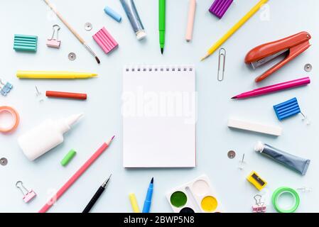 Notizbuch mit stationären Objekten im blauen Hintergrund. Zurück in die Schule mit Schreibwaren, Notizbuch und Schere auf dem Schreibtisch Hintergrund Draufsicht moc Stockfoto
