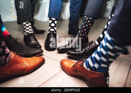 Nahaufnahme von Männern Beine tragen formelle Schuhe und lustige bunte Socken. Sieben Freunde Füße in Kreis Komposition. Stockfoto