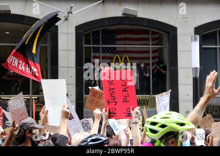 Protestler, die Zeichen halten, marschieren auf Broadway vorbei an den Fenstern des McDonald's Restaurants in Manhattan Downtown, New York, NY, USA - 2. Juni 2020 Stockfoto