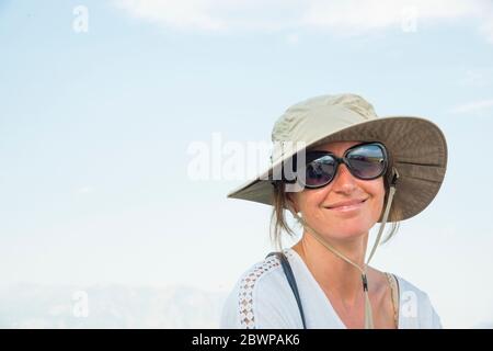 Junge Frau in einem Sonnenhut sitzend und posiert auf Ein geteilter Schienenzaun auf einer Ranch Stockfoto