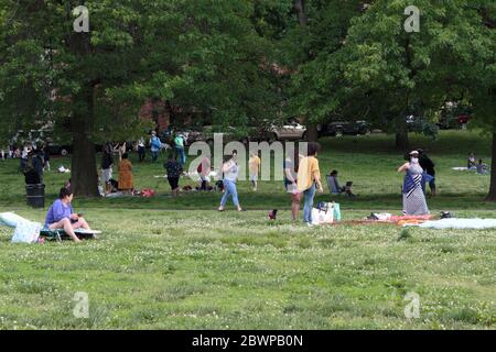 Leute, die sich im Inwood Hill Park entspannen, einige mit Masken, andere ohne, am Wochenende Stockfoto