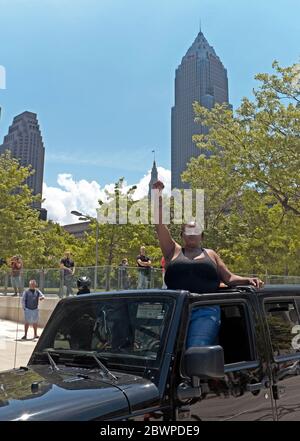 Eine schwarze Frau mit erhobener Faust steht im Auto und zeigt ihre Unterstützung für die nahe gelegene Bewegung „Black Lives Matter“, die sich am 30. Mai 2020 in Cleveland, Ohio, versammelt. Stockfoto