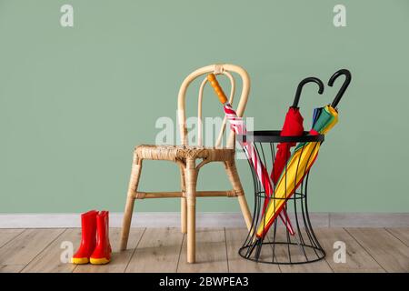 Sonnenschirme, Stuhl und Stiefel in der Nähe von Farbwand Stockfoto