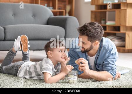 Kleiner Junge und Vater mit Ersparnissen für die Bildung zu Hause Stockfoto