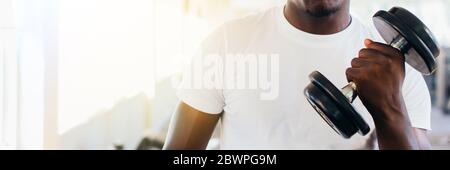 Junge afrikanische amerikanische Mann stehen und heben eine Hantel mit dem Rack im Fitnessstudio. Männliche Person, ein Krafttraining Bizeps in Fitnesscenter curl Stockfoto
