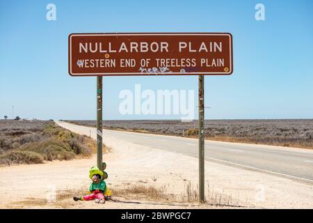 Nullarbor Plian Australien 16. November 2019 : Leprachaun Puppe sitzt an der Basis des berühmten Nullarbor Plain Zeichen in Western Australia Stockfoto