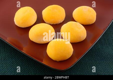 Nahaufnahme von Mango-Eis-Mochi-Kugeln auf roter Servierplatte Stockfoto