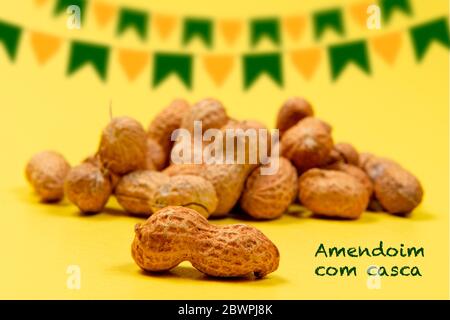 Erdnusshaufen in Schale (Text auf Portugiesisch) auf gelbem Hintergrund. Typische Prise Juni Party (Festa Junina) Stockfoto