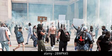 Cleveland, Ohio, USA. Mai 2020. Ein weißer Mann geht durch eine vielfältige Menge von Demonstranten, die von der Cleveland Polizei während der George Floyd Demonstrationen in Cleveland, Ohio, USA, vergast werden. Tausende von Demonstranten marschierten zum Justizzentrum an der Lakeside Avenue, wo die Proteste gewalttätig wurden, bevor sie sich in der Innenstadt ausbreiteten. Schwarze Leben sind wichtig, soziale Gerechtigkeit und Reform der Polizeikultur sind viele der Themen, die in dem Protest gipfelten. Cleveland ist eine von vielen Städten in den Vereinigten Staaten und auf der ganzen Welt, die gegen Polizeibrutalität in den Vereinigten Staaten protestieren. Stockfoto