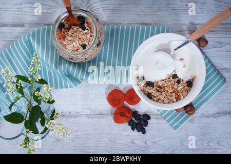 Gesundes Frühstück: Rosinen, getrocknete Aprikosen, Nüsse, Haferflocken, Joghurt und frisches Obst Stockfoto